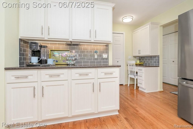 468 Orchard Ridge Dr, Lake Orion, MI 48362 - kitchen featuring freestanding refrigerator, light wood finished floors, white cabinetry, decorative backsplash, and dark stone counters