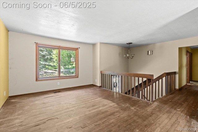 13041 Big Lake Rd, Davisburg, MI 48350 - unfurnished room with a chandelier, wood finished floors, baseboards, and a textured ceiling