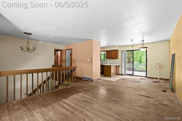 13041 Big Lake Rd, Davisburg, MI 48350 - unfurnished living room with a chandelier, light wood-style floors, baseboards, and a textured ceiling