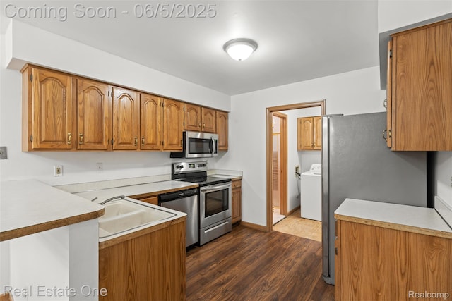 2343 Heritage Pointe Dr Unit 29, Sterling Heights, MI 48314 - kitchen featuring appliances with stainless steel finishes, a peninsula, dark wood finished floors, brown cabinets, and washer and clothes dryer