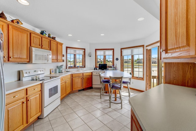 3547 Sand Bar Ct, Muskegon, MI 49441 - kitchen featuring white appliances, a peninsula, light countertops, light tile patterned floors, and recessed lighting
