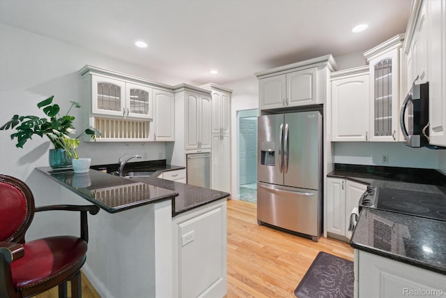 8883 Dixie Hwy, Birch Run, MI 48415 - kitchen with appliances with stainless steel finishes, a peninsula, light wood-style flooring, glass insert cabinets, and a kitchen bar