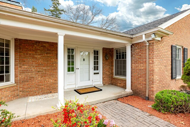 1060 Chestnut St, Ann Arbor, MI 48104 - doorway to property featuring brick siding, a porch, and a shingled roof