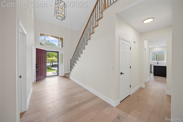4610 Woodbine Cir W, Bloomfield, MI 48323 - entryway with light wood-style flooring, a chandelier, baseboards, stairway, and a towering ceiling