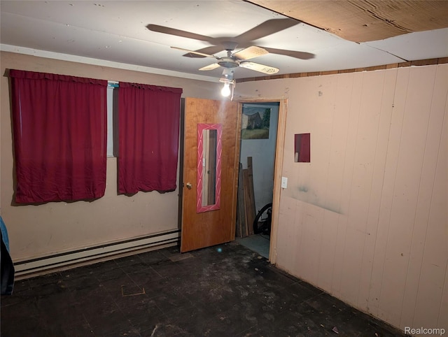 150 University Dr, Howell, MI 48843 - empty room featuring a baseboard heating unit, a ceiling fan, electric panel, and wooden walls