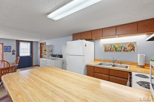 8400 Horton Beach Dr, Manitou Beach, MI 49253 - kitchen with white appliances, a textured ceiling, washer and clothes dryer, a sink, and brown cabinets