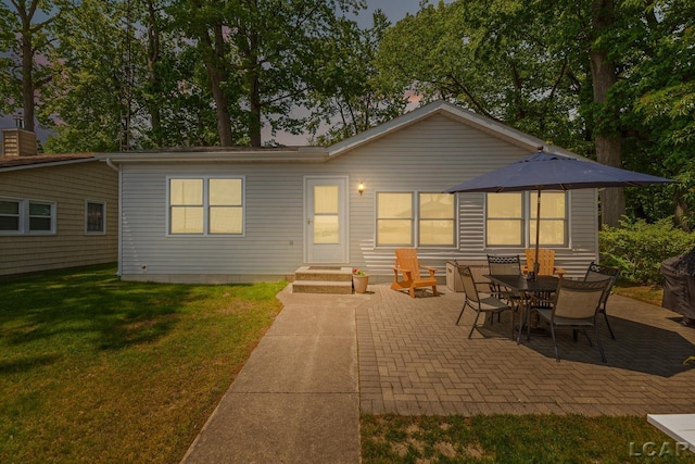8400 Horton Beach Dr, Manitou Beach, MI 49253 - back of property at dusk featuring a patio and a yard