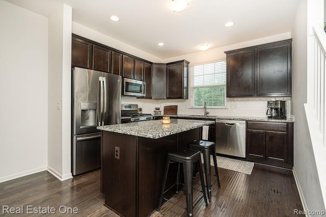4661 Bradley Cir, Troy, MI 48085 - kitchen featuring appliances with stainless steel finishes, baseboards, dark brown cabinetry, dark wood finished floors, and a kitchen bar