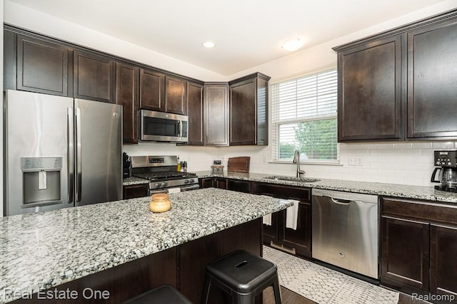 4661 Bradley Cir, Troy, MI 48085 - kitchen with stainless steel appliances, a sink, light stone counters, dark brown cabinetry, and recessed lighting