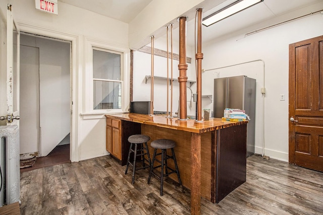26 Harvard St, Battle Creek, MI 49017 - kitchen featuring wood counters, freestanding refrigerator, dark wood-style floors, brown cabinetry, and a kitchen bar