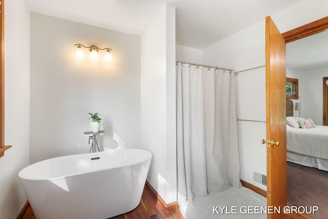 2229 Brighton St, Holland, MI 49424 - bathroom with ensuite bathroom, baseboards, a shower with shower curtain, wood finished floors, and a soaking tub