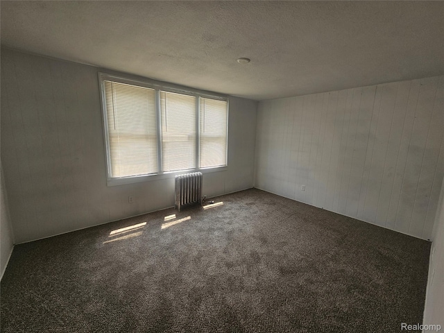 48 W Charlotte St, Ecorse, MI 48229 - carpeted spare room featuring radiator heating unit, wood walls, and a textured ceiling