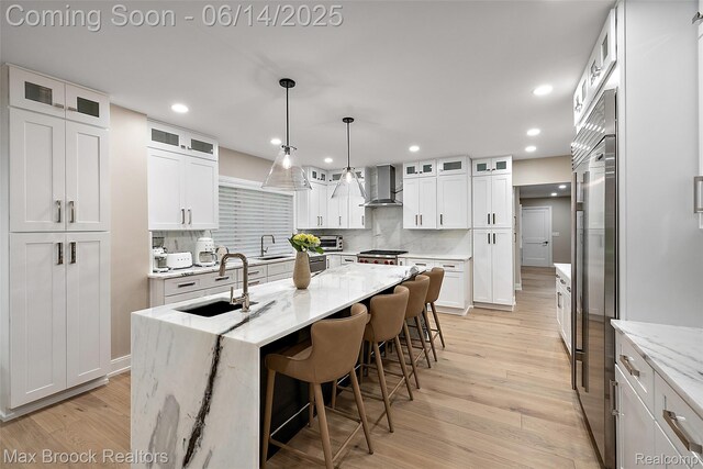 3546 Bloomfield Club Dr, Bloomfield Hills, MI 48301 - kitchen with a sink, wall chimney range hood, light wood-type flooring, a kitchen island with sink, and backsplash