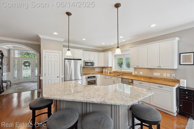 446 Delmar Ct, Highland, MI 48357 - kitchen featuring appliances with stainless steel finishes, a sink, decorative backsplash, white cabinets, and light wood-style floors