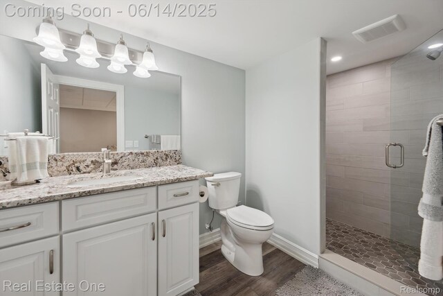 446 Delmar Ct, Highland, MI 48357 - bathroom with vanity, wood finished floors, a shower stall, toilet, and baseboards