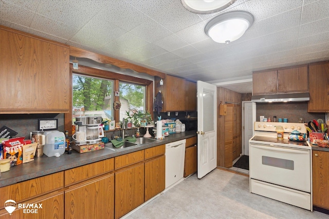 7131 Houghton Dr, Davison, MI 48423 - kitchen with white appliances, under cabinet range hood, a sink, dark countertops, and brown cabinetry