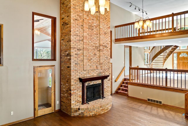 4693 Gallagher Rd, Rochester, MI 48306 - unfurnished living room featuring a chandelier, a towering ceiling, wood-type flooring, stairway, and a fireplace