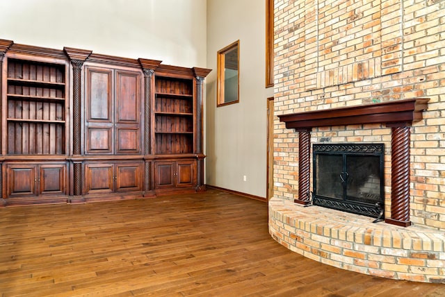 4693 Gallagher Rd, Rochester, MI 48306 - unfurnished living room with wood-type flooring, a brick fireplace, a high ceiling, and baseboards