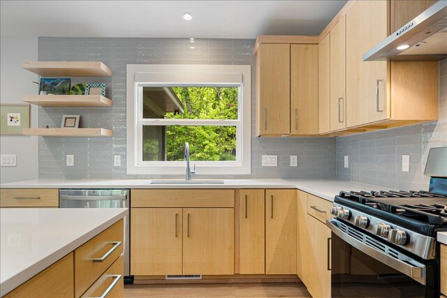 4067 Hillside Trl, New Buffalo, MI 49117 - kitchen with appliances with stainless steel finishes, light brown cabinetry, under cabinet range hood, a sink, and light countertops