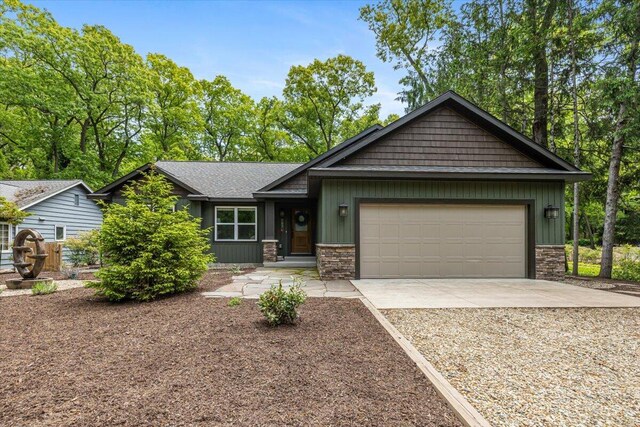 4067 Hillside Trl, New Buffalo, MI 49117 - view of front of house featuring concrete driveway, stone siding, an attached garage, and board and batten siding