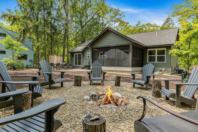 4067 Hillside Trl, New Buffalo, MI 49117 - rear view of property featuring a fire pit, a sunroom, a shingled roof, and a patio