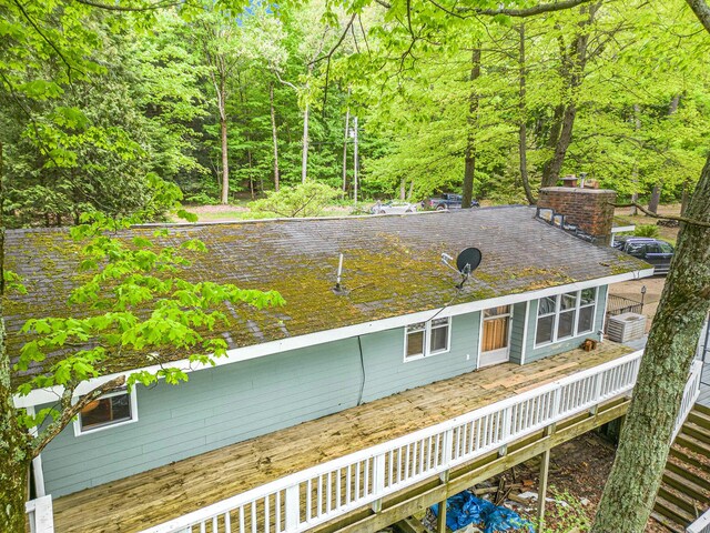 4468 Teal Ln, Newaygo, MI 49337 - rear view of house with a deck, central air condition unit, a chimney, and a wooded view