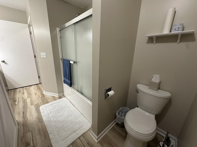 335 Nestlewood Dr, Holland, MI 49424 - bathroom featuring wood finished floors, toilet, shower / bath combination with glass door, and baseboards