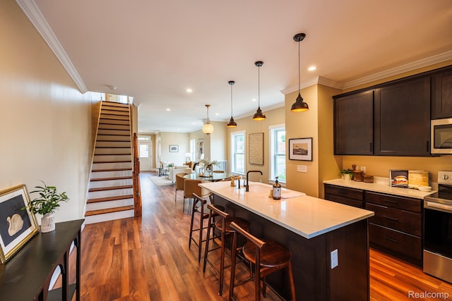 215 W Fifth Ave Unit 2, Flint, MI 48502 - kitchen featuring stainless steel appliances, a kitchen breakfast bar, dark wood finished floors, dark brown cabinetry, and ornamental molding