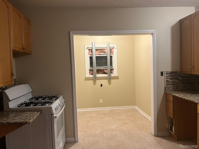 18815 Lancashire St, Detroit, MI 48223 - kitchen featuring gas range gas stove, light tile patterned flooring, baseboards, and dark stone counters