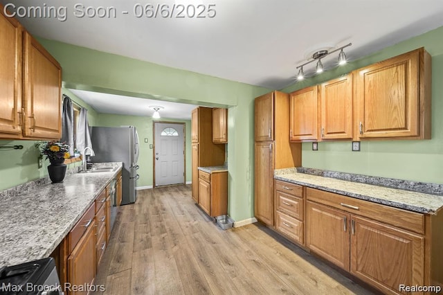 7713 Jackson St, Taylor, MI 48180 - kitchen with light wood-type flooring, a sink, light stone counters, and brown cabinets
