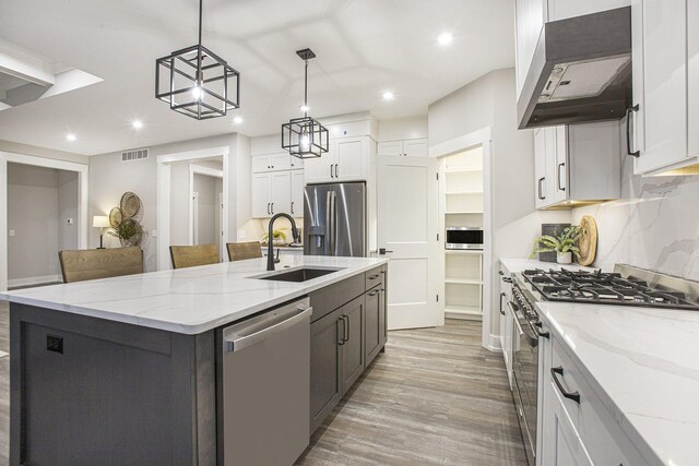 2748 Woodhaven Ct SW Unit 03, Byron Center, MI 49315 - kitchen featuring stainless steel appliances, wall chimney exhaust hood, a sink, recessed lighting, and light wood finished floors
