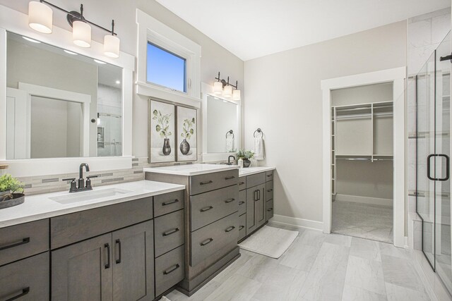 2748 Woodhaven Ct SW Unit 03, Byron Center, MI 49315 - bathroom with a shower stall, two vanities, tasteful backsplash, and a spacious closet