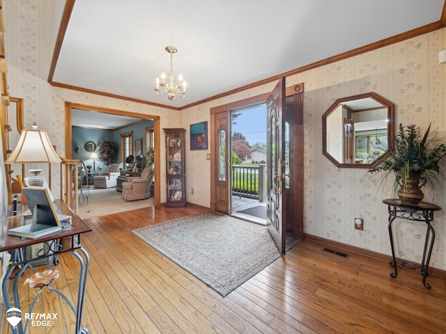9705 Burning Tree Dr, Grand Blanc, MI 48439 - foyer featuring wallpapered walls, wood-type flooring, a chandelier, and ornamental molding