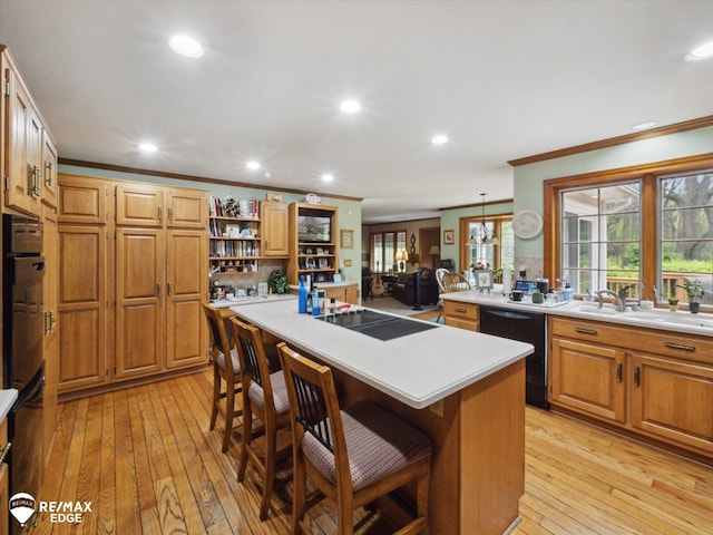 9705 Burning Tree Dr, Grand Blanc, MI 48439 - kitchen featuring black appliances, ornamental molding, light countertops, light wood-style flooring, and a breakfast bar area