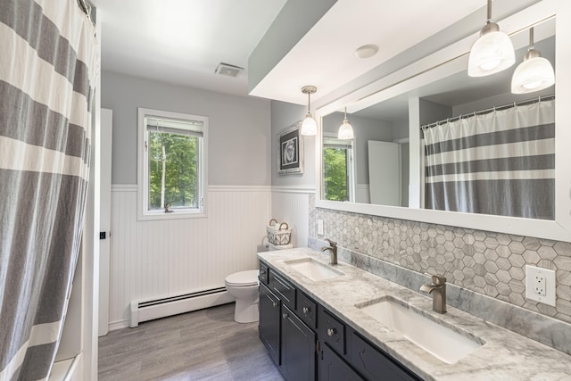 8680 Bennett St SE, Ada, MI 49301 - full bath with a baseboard radiator, a wainscoted wall, wood finished floors, double vanity, and toilet