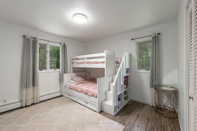 8680 Bennett St SE, Ada, MI 49301 - bedroom featuring a baseboard heating unit, wood finished floors, and baseboards