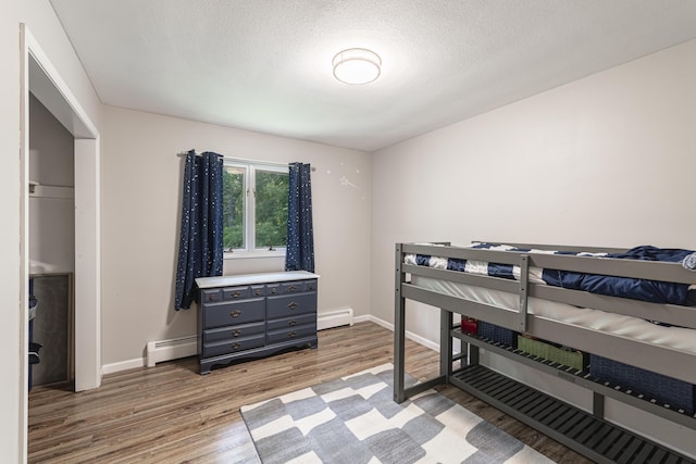 8680 Bennett St SE, Ada, MI 49301 - bedroom with light wood-type flooring, baseboard heating, and baseboards