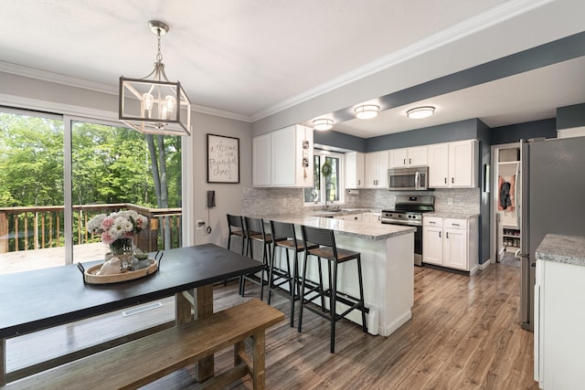 8680 Bennett St SE, Ada, MI 49301 - kitchen featuring appliances with stainless steel finishes, a peninsula, decorative backsplash, white cabinetry, and crown molding