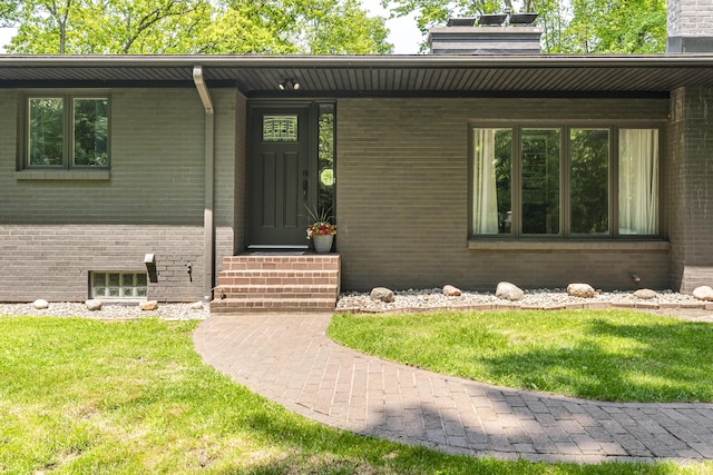 8680 Bennett St SE, Ada, MI 49301 - view of exterior entry with brick siding, a chimney, and a yard