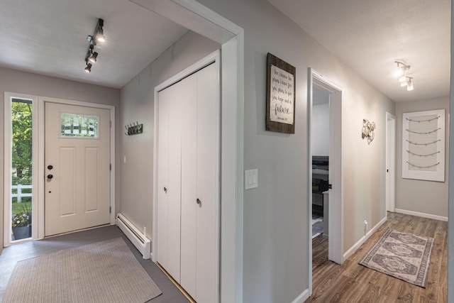 8680 Bennett St SE, Ada, MI 49301 - entryway featuring a baseboard heating unit, rail lighting, dark wood-type flooring, and baseboards
