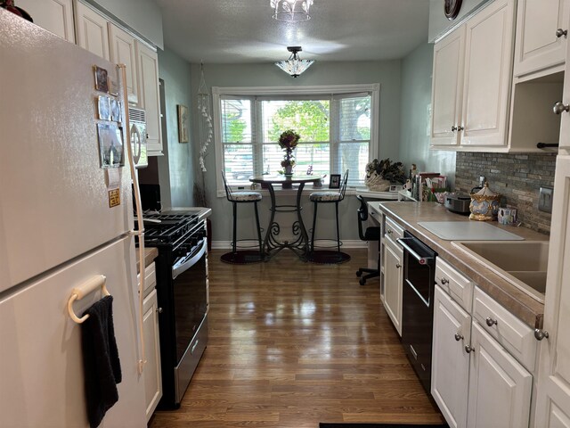 249 Churchgrove Rd, Frankenmuth, MI 48734 - kitchen with freestanding refrigerator, stainless steel gas stove, dark wood-style floors, tasteful backsplash, and white cabinetry