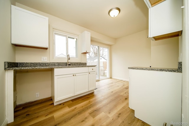 15400 Sprenger Ave, Eastpointe, MI 48021 - kitchen with light wood-style floors, white cabinets, dark stone countertops, and baseboards