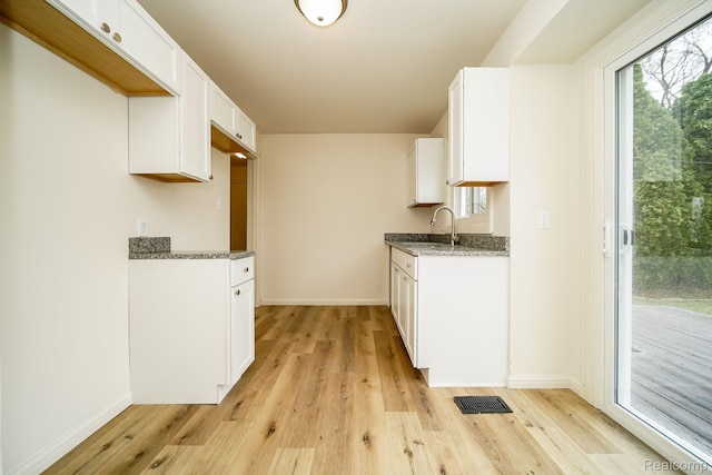 15400 Sprenger Ave, Eastpointe, MI 48021 - kitchen featuring light wood-style flooring, a sink, and dark stone countertops