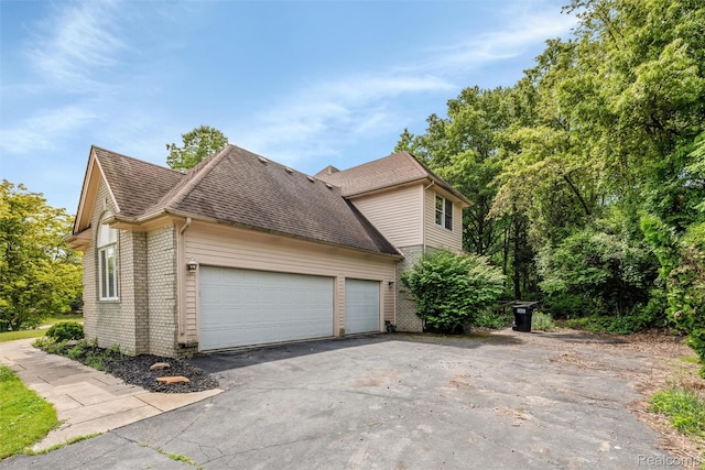 2479 Waterfront Dr, Brighton, MI 48114 - view of home's exterior with driveway, brick siding, a shingled roof, and an attached garage