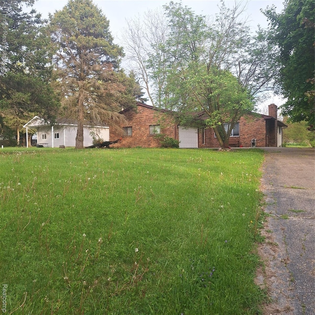 3827 Woodland Dr, Metamora, MI 48455 - view of front of property featuring a chimney, driveway, a front lawn, and brick siding
