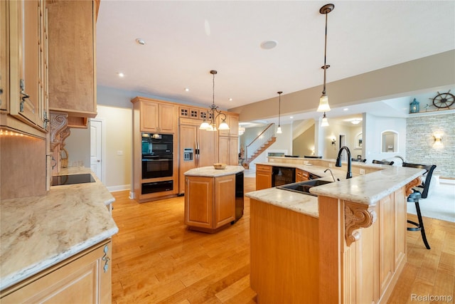 6312 S Graham Rd, Saint Charles, MI 48655 - kitchen with a sink, a large island with sink, black appliances, a warming drawer, and light wood-type flooring