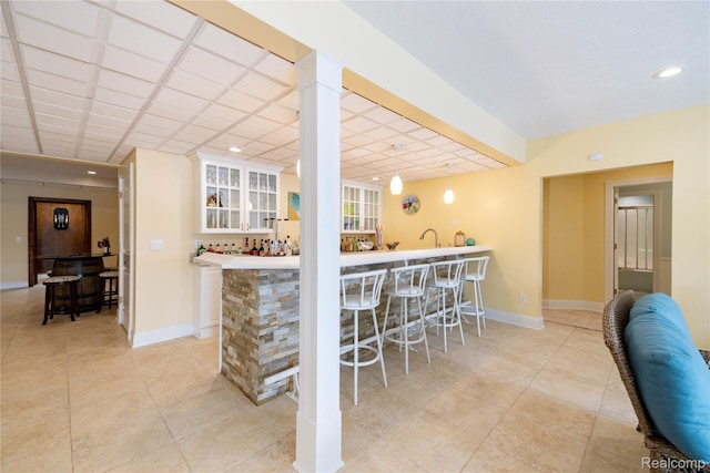 6312 S Graham Rd, Saint Charles, MI 48655 - kitchen featuring white cabinetry, glass insert cabinets, baseboards, light tile patterned floors, and light countertops
