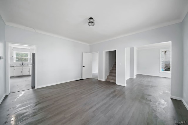 603 Company St, Adrian, MI 49221 - unfurnished living room featuring a sink, stairway, baseboards, and dark wood-type flooring
