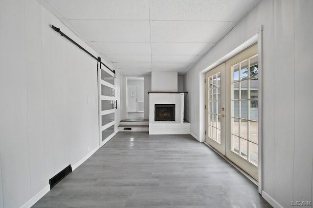603 Company St, Adrian, MI 49221 - unfurnished living room with a barn door, french doors, a paneled ceiling, and baseboards