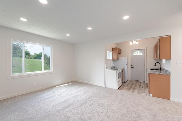 607 S Mill St, Saint Louis, MI 48880 - kitchen with white appliances, a sink, light colored carpet, brown cabinets, and recessed lighting